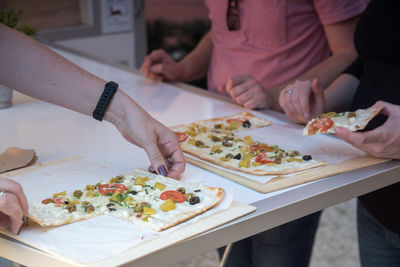 Midsection of friends eating pizza on table