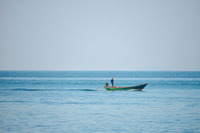 Man on boat in sea against clear sky