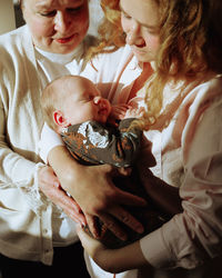 High angle view of mother carrying baby and standing together with her mother at home