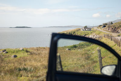 Cropped image of car door against sea