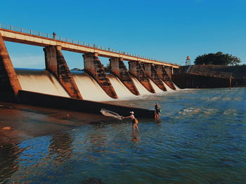 Bridge over river against clear blue sky