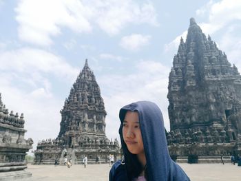 Woman in hooded shirt against old temples