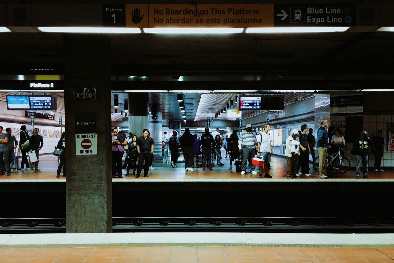 public transportation, railroad station, transportation, railroad station platform, large group of people, rail transportation, men, person, subway station, text, railroad track, indoors, travel, mode of transport, passenger, train - vehicle, lifestyles, city life, transportation building - type of building