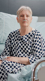 Portrait of smiling young woman sitting on bed at home