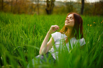 Portrait of young woman sitting on grassy field