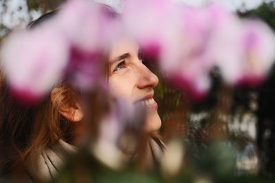 Smiling woman looking away by blooming flowers