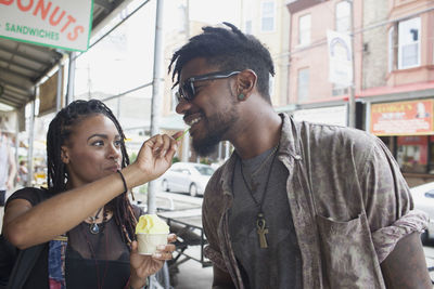 A young woman feeiding a young man frozen yogurt.