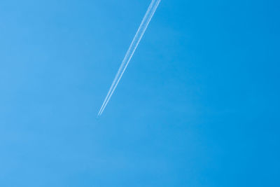 Airplane flying in the clear blue sky with white trail along the route