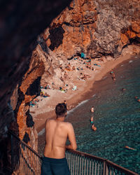 Rear view of shirtless man standing on rock