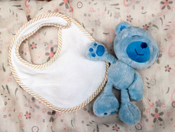 High angle view of baby bib and stuffed toy on fabric