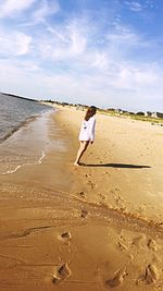 Rear view of woman standing on beach during sunny day