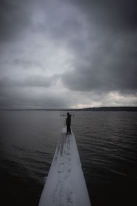 Man standing on pier over sea against sky