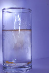 Close-up of glass of water against blue background
