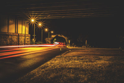 Light trails on road against sky at night