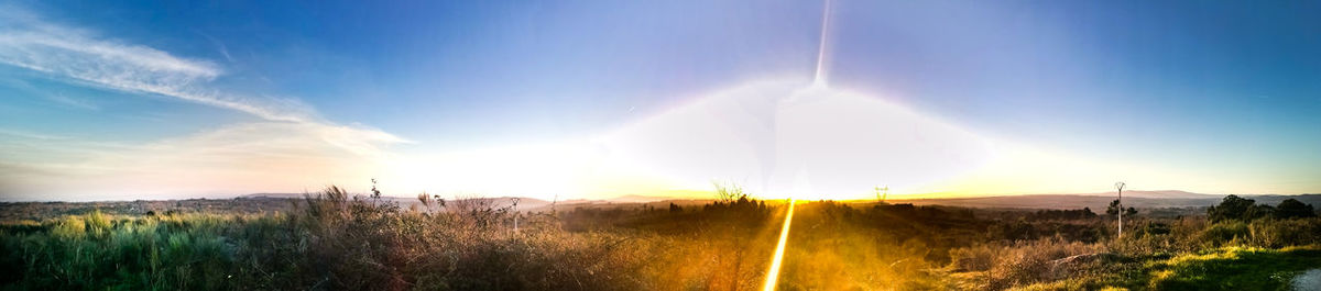 Sunlight streaming on field against sky during sunset