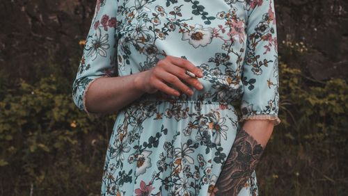 Midsection of woman standing by bare tree on field