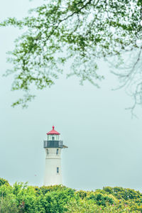 Lighthouse by sea against sky