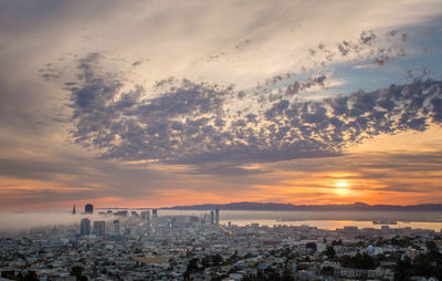 Aerial view of buildings against cloudy sky at sunset