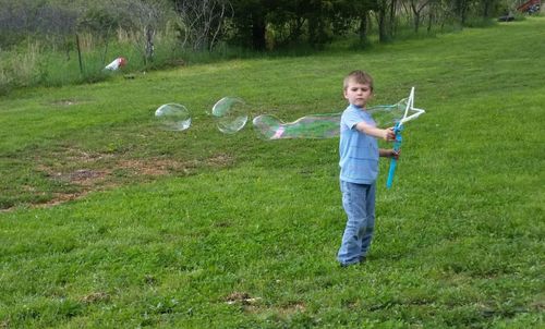 Full length of boy making bubbles on grassy land