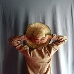 Midsection of woman holding hat against wall