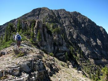 Rear view of person on rock against sky