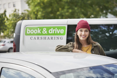 Beautiful young woman leaning on car