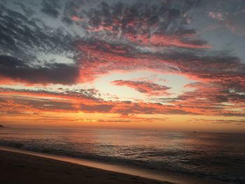 Scenic view of sea against dramatic sky during sunset