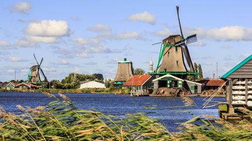 Traditional windmill by river against sky