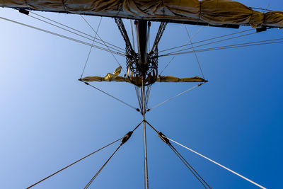 Low angle view of electricity pylon against clear blue sky