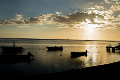 Silhouette boats in sea against sky during sunset