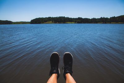 Low section of person over lake against sky