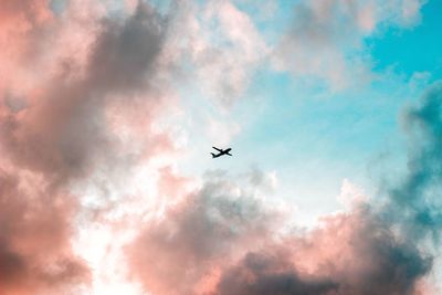 Low angle view of silhouette airplane flying in sky during sunset