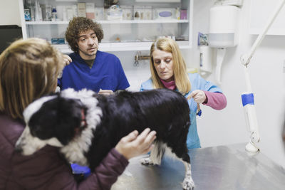 Back view of client leaving dog on table for veterinarians in surgery room