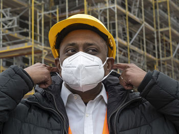 Indian construction worker putting on a protective ffp2 mask, outdoors