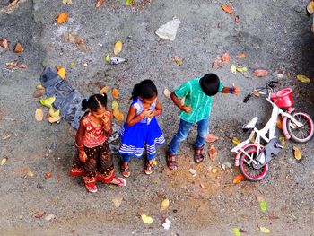High angle view of children standing on road by bicycle