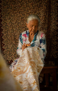 Rear view of woman sitting on bed at home