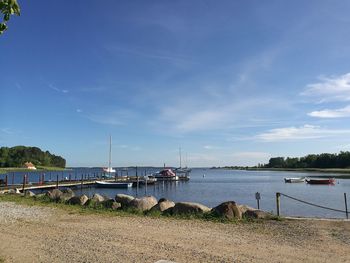 Boats moored at harbor against blue sky