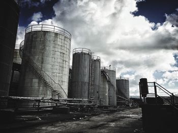 Low angle view of factory against cloudy sky