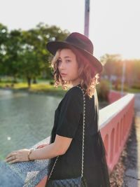 Young woman standing by lake in park
