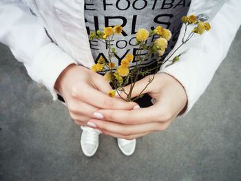 Low section of man holding yellow flowers on street