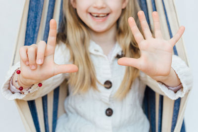 Midsection of smiling girl standing against wall