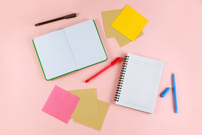 Directly above shot of diary and pens on pink background