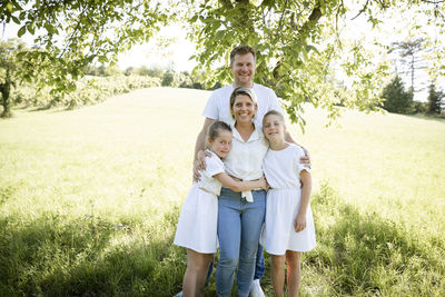 Portrait of smiling mother and daughter standing on field