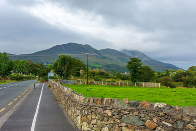 Road leading towards mountains against sky