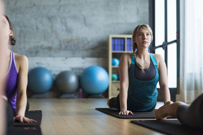 Women practicing upward facing dog position in gym