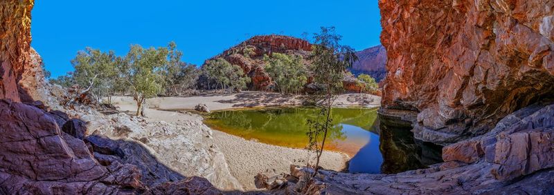 Scenic view of lake and rocks against clear blue sky