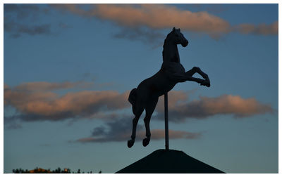 Low angle view of silhouette statue against sky