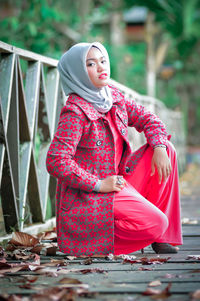 Portrait of young woman sitting on railing