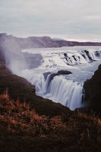 Scenic view of waterfall against sky