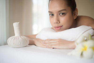 Portrait of smiling young woman lying on massage table in spa